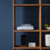 Household goods occupy a modular wooden shelving frame in a realistic editorial photograph.