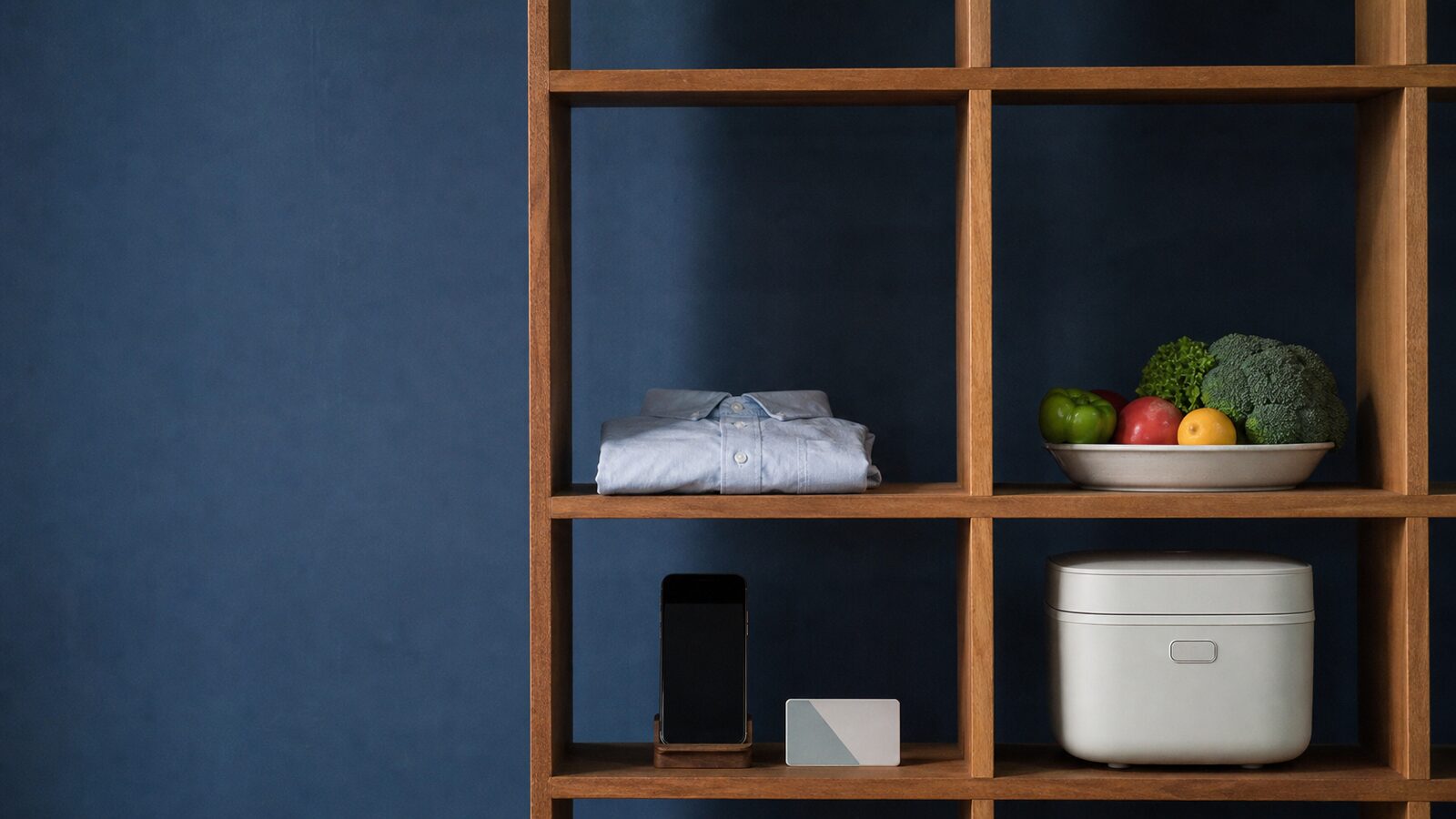 Household goods occupy a modular wooden shelving frame in a realistic editorial photograph.