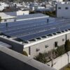 Wide view of rooftop solar panels on a low-rise commercial building under clear afternoon light with no logos or signs.