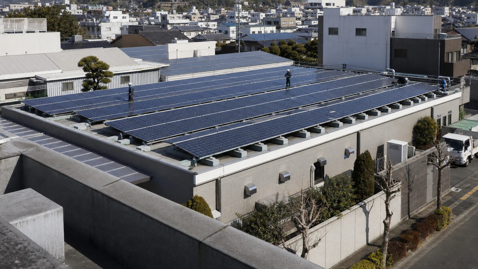 Wide view of rooftop solar panels on a low-rise commercial building under clear afternoon light with no logos or signs.