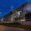 Semiconductor fabrication campus with service pipes and warm lights at blue hour