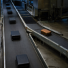 One amber suitcase diverts onto a side conveyor in a quiet airport baggage hall.