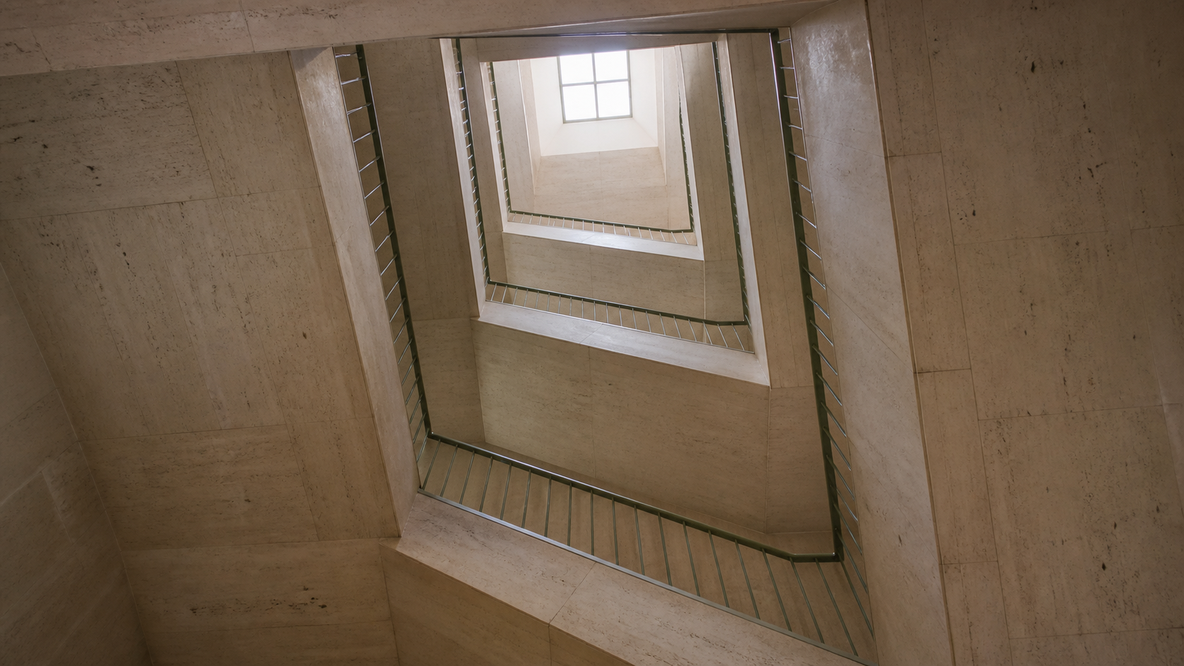 Four concrete landings rise through a skylit office stairwell.