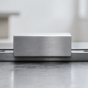 Blank brushed-metal carriage centered between two red stops on a worn linear workshop rail.