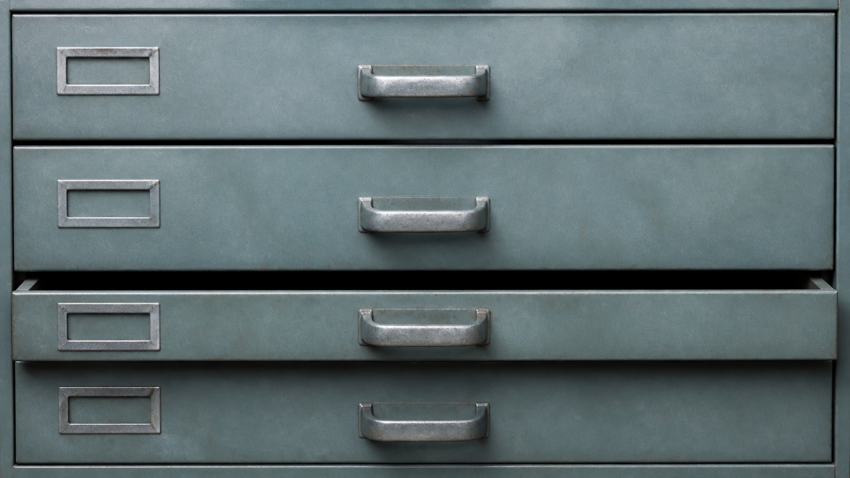 Four blank steel archive drawers with one compartment slightly open in a worn records cabinet.