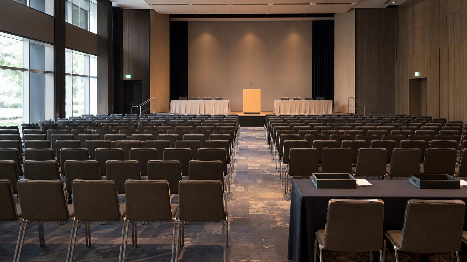 Empty conference hall prepared for a Japanese shareholder meeting with an unbranded stage and rows of seats.