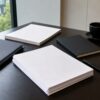Blank folders, papers and a notebook on an investor research desk near a window.