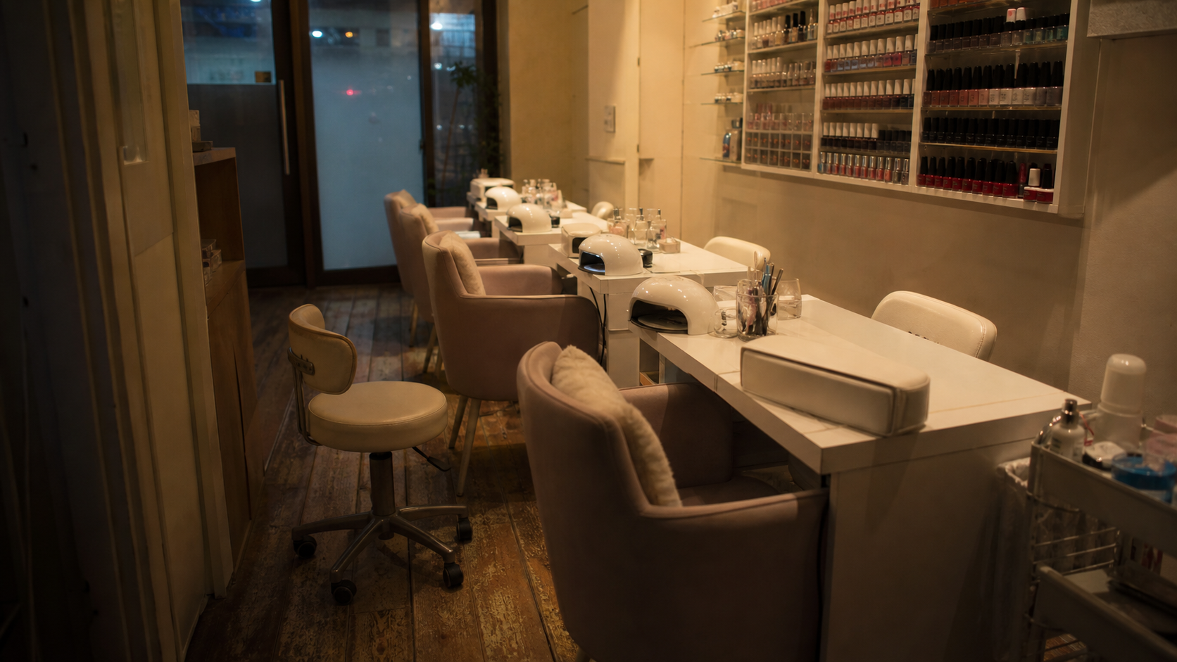 An empty unbranded nail salon after closing with manicure stations and plain polish bottles.