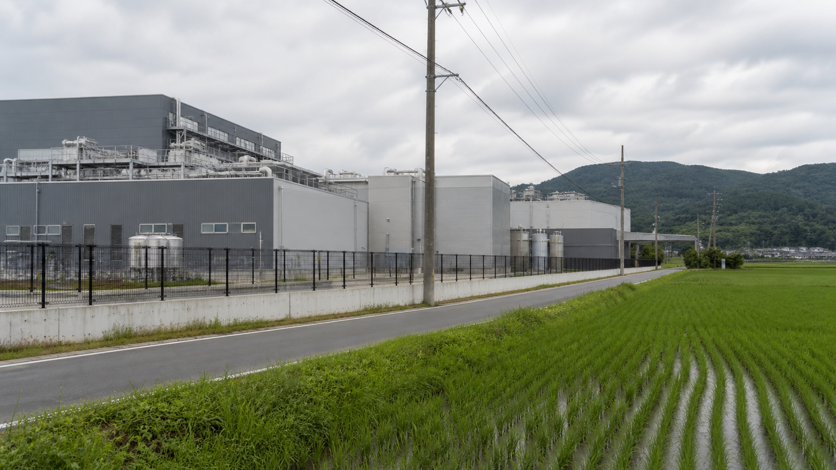 Industrial semiconductor facility beside green fields and wooded hills