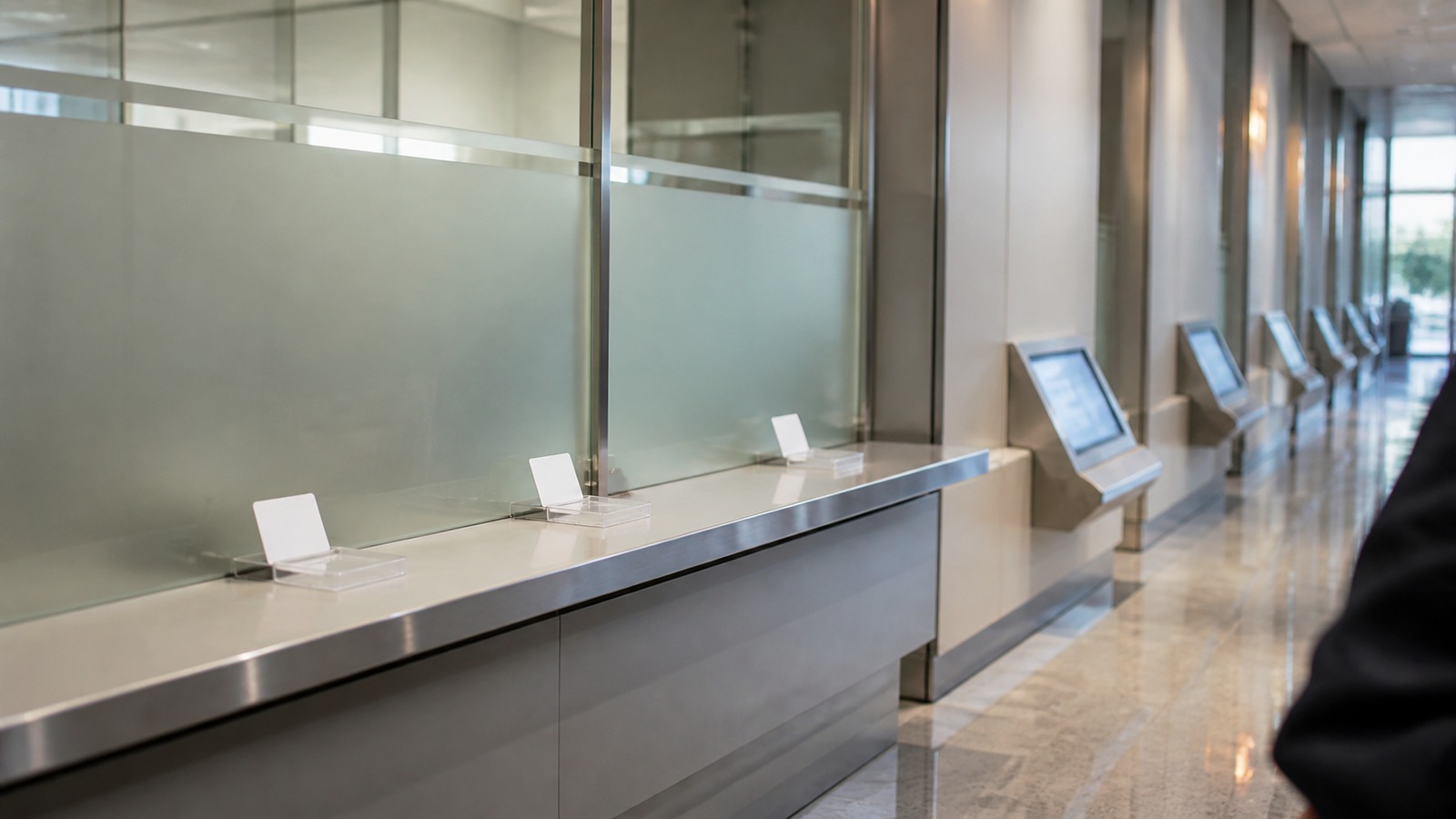 Unbranded information counter with blank access cards and unreadable terminals in a glass corridor.