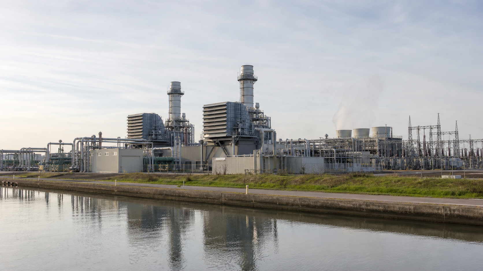 Unbranded combined-cycle power station beside a canal in daylight