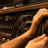 Sound engineer routing unbranded braided audio cables through a recording-studio patch bay