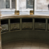 An unbranded curved currency-exchange counter with muted green metal cash drawers