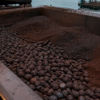Iron ore pellets and dark fines in a weathered open freight hopper beside a coastal terminal