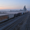 Unbranded freight train and parallel tracks crossing a misty rural rail yard at dawn