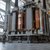 Unbranded high-voltage transformer assembly inside a large industrial hall.