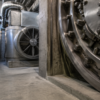 Unbranded steel vault mechanism and ventilation equipment in a quiet concrete service corridor