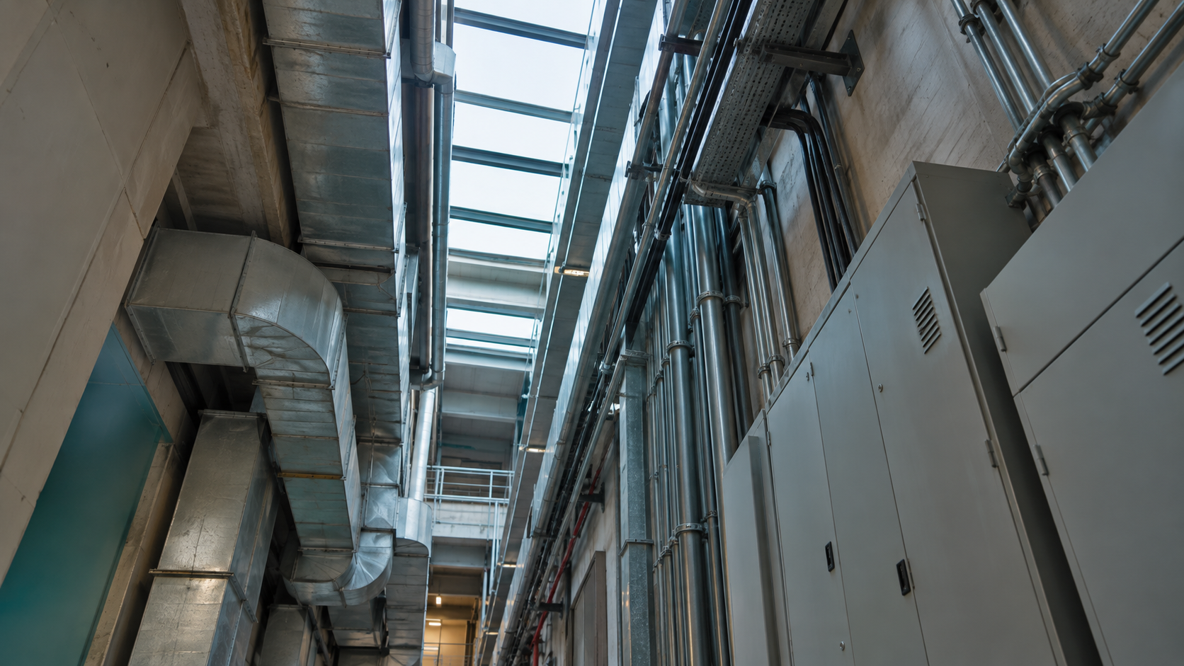 Separate utility conduits and ventilation ducts run through an anonymous commercial service corridor.