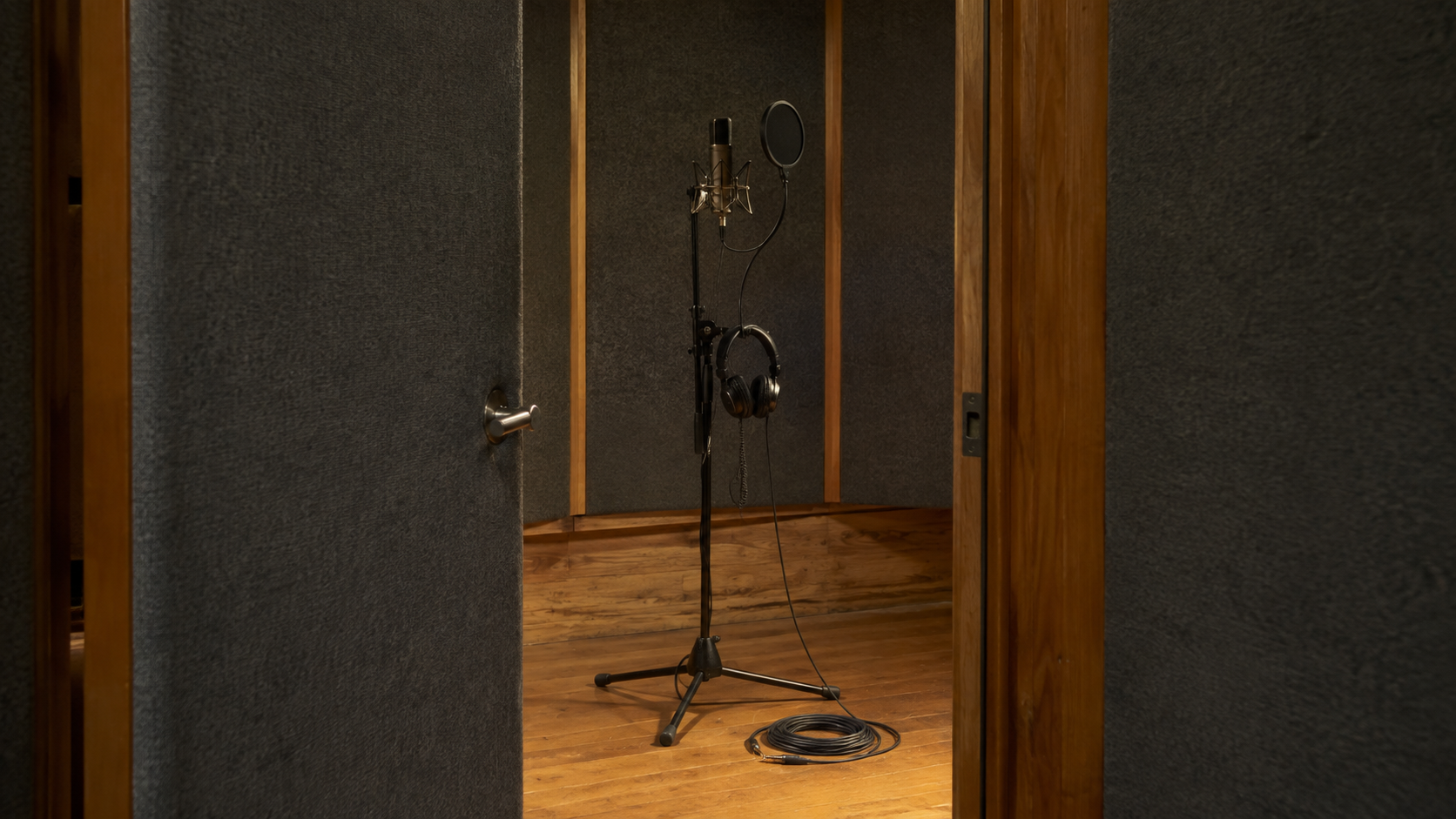 Unbranded recording booth with a microphone, headphones and coiled cable
