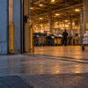 An unbranded sorting-facility loading bay at dawn, with a rolling cage of plain envelopes inside.
