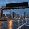 Blank variable speed-limit gantry above a wet elevated urban road at blue hour