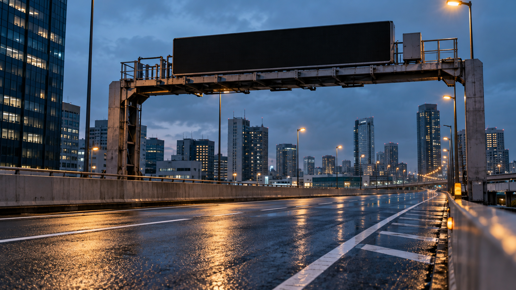 Blank variable speed-limit gantry above a wet elevated urban road at blue hour