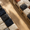 Overhead view of neatly folded unbranded knitwear on wooden shelves beside a sunlit aisle.