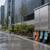 A rain-speckled unbranded fiber-optic junction cabinet beside a modern data-center building.