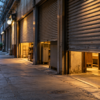 A quiet unbranded covered retail arcade with shop shutters opening before dawn.